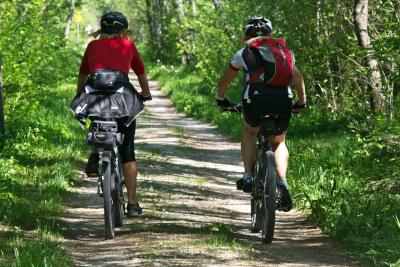 Zwei Radfahrende auf einem Schotterweg im Wald