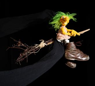 Die Puppe der Hexe Hilda sitzt auf einem Reisigbesen und fliegt durch die Luft