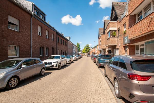 Straße mit parkenden Autos und Wohnhäusern