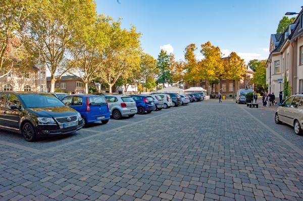Parkende Autos auf Parkplatz mit Bäumen im Hintergrund
