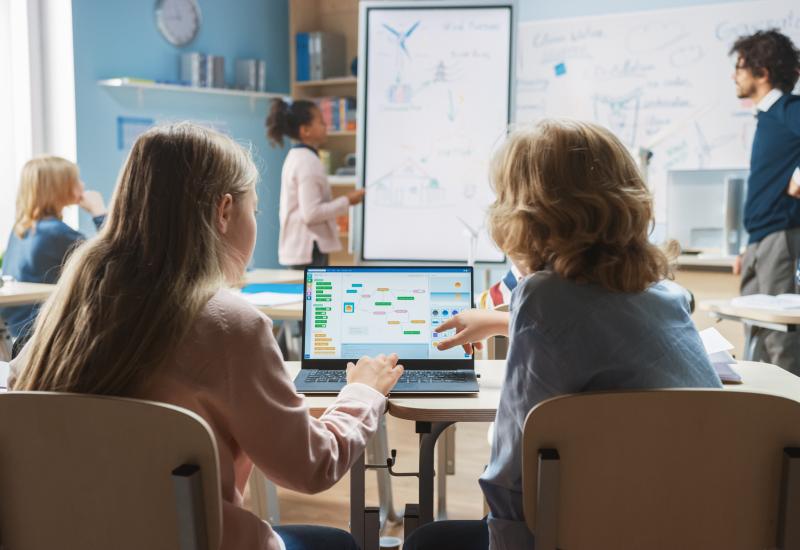 2 Schulkinder arbeiten im Klassenraum an einem Notebook